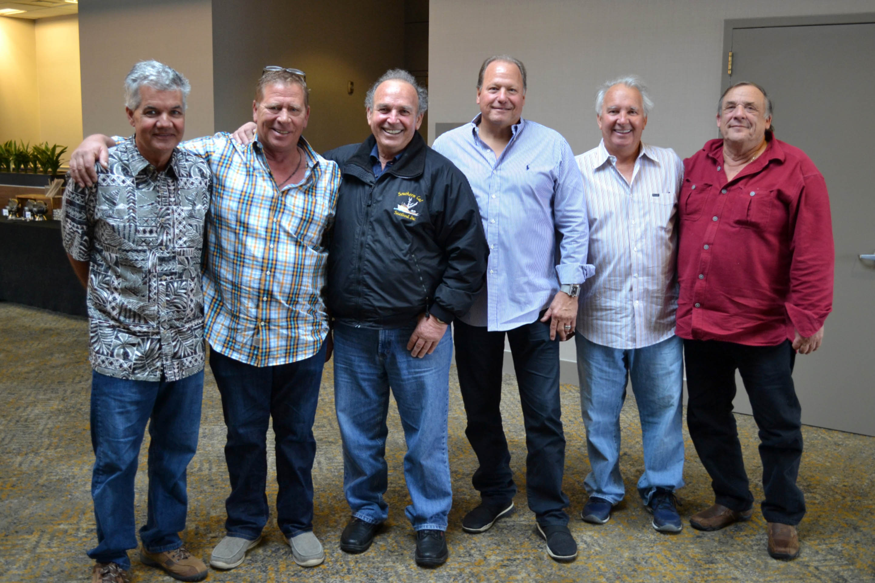 Six men, all fishermen, stand smiling at the camera