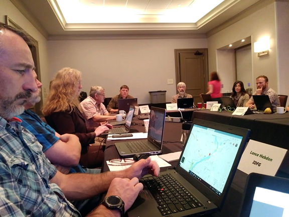 A man in a meeting looks at a computer.