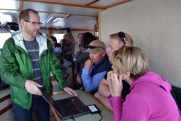 Members of the Council staff gather around a computer screen to learn about electronic monitoring.