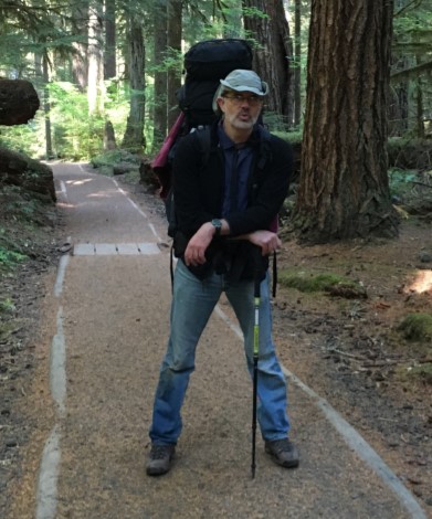 A man with a backpack poses on a trail