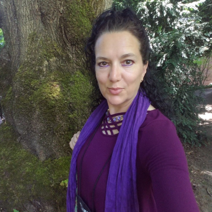 A woman wearing a purple shirt and purple scarf smiles for the camera