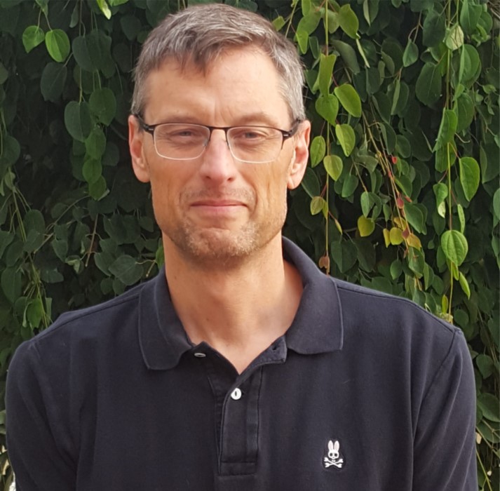 A man wearing glasses and a black shirt smiles for the camera