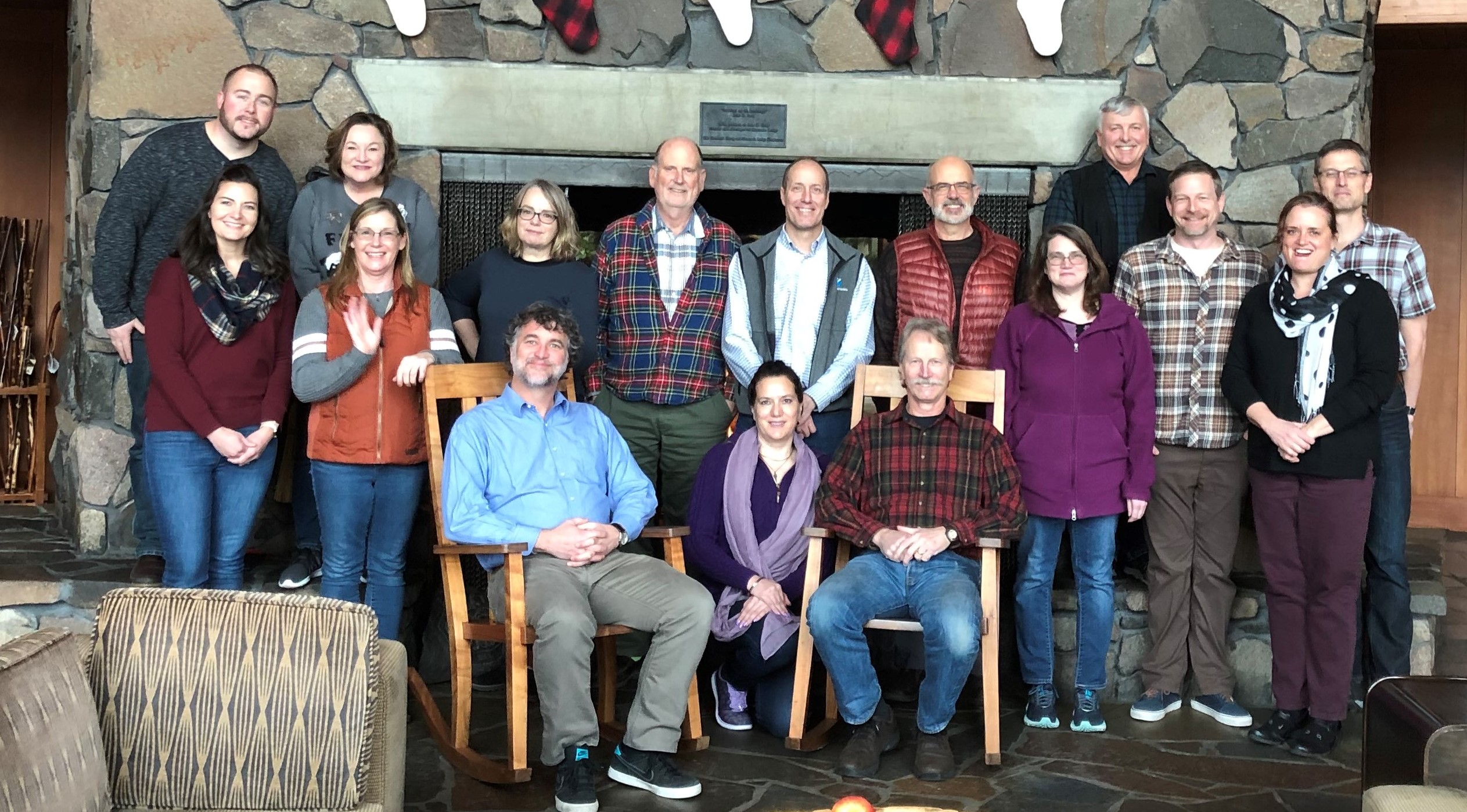 16 people stand in front of a fireplace
